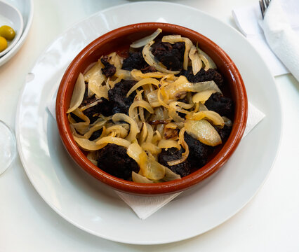 Delicious Catalan blood sausages with grilled onion served on clay plate. Morcilla con cebolla
