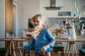 Young girl joyfully dances amidst Easter decorations in a festive dining room