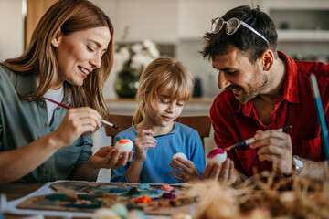 Mom, dad, and daughter create colorful masterpieces in their dining room