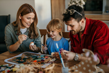 Loving caucasian family of three bonds over Easter egg decorating in their cozy dining room