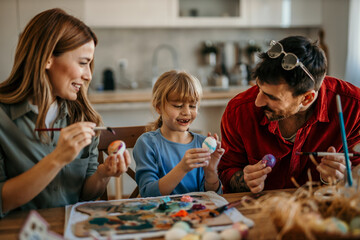 Family of three bonds over Easter egg decorating in their cozy dining room