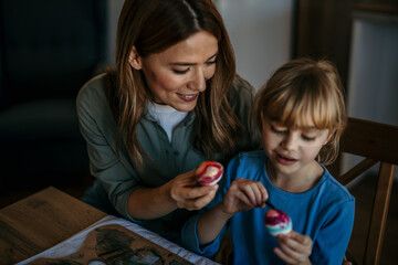 Joyful mother and daughter adding festive touches to their Easter celebration