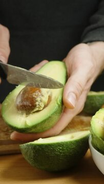 With a swift knife motion, a man strikes the pit of the avocado and extracts it a life hack for peeling avocados.