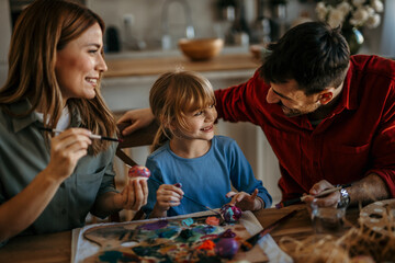 Smiling family enjoys decorating eggs as they prepare for the holiday