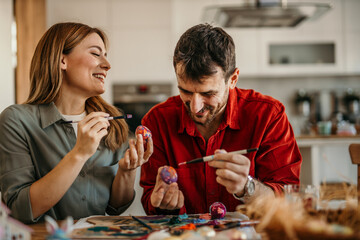 Smiling pair creating Easter crafts amidst a backdrop of festive dining room decor