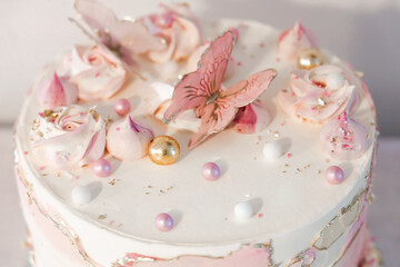 Fototapeta na wymiar Birthday cake decorated with pink sugar flowers and butterflies.