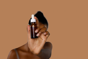 Black Woman Showing Golden Serum Skin Care Bottle