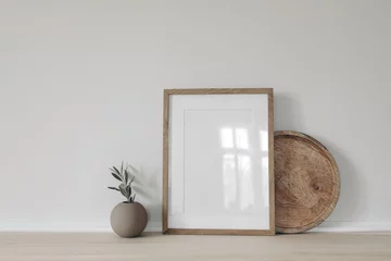 Gordijnen Blank vertical picture frame mockup, poster display. Ball vase with olive tree branch. Round wooden tray on table, desk. Minimal rustic home. Scandinavian interior. White wall background. © tabitazn