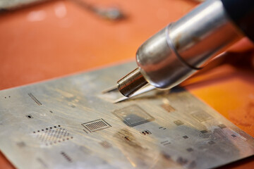 close up view of soldering iron near microscheme of digital device in workshop, repair business