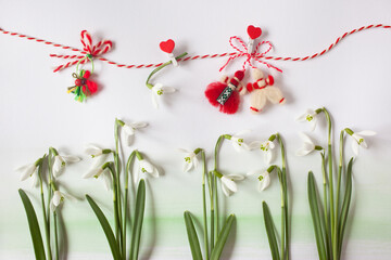 Snowdrop flowers and red and white martenitsa symbols of the March 1st Martisor holiday on white paper. - 728864949