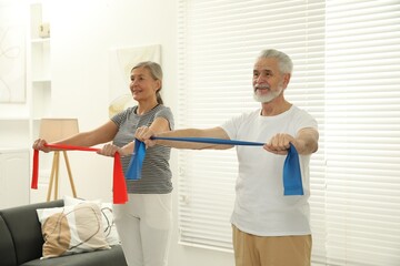 Senior couple doing exercise with fitness elastic bands at home