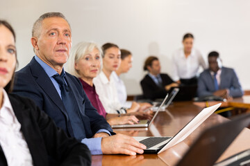 Focused caucasian man listening to lecture at conference in meeting room
