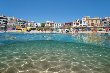 Spain, beach in the Mediterranean village of Calella de Palafrugell seen from sea surface with sand underwater, split view half over and under water, natural scene, Costa Brava, Catalonia - obrazy, fototapety, plakaty