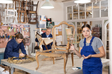 Fototapeta na wymiar Female restorer restores the wooden frame of an antique chair