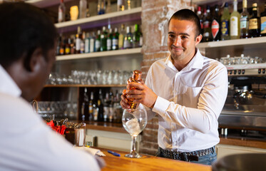 Bartender shaking cocktail for friends, they drinking in nightclub