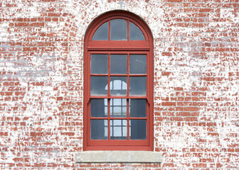 Obraz premium Red framed window inside a window with old red brick facade.