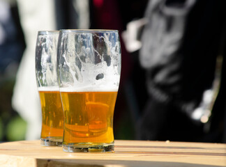 two glasses of craft lager beer on wooden table with blur background