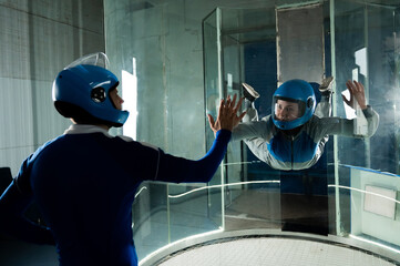 A male instructor teaches a woman how to fly in a wind tunnel. Free fall simulator.