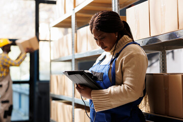 African american woman supervising stock supply using barcode scanner and digital tablet. Warehouse distribution manager checking inventory and scanning products in storage room