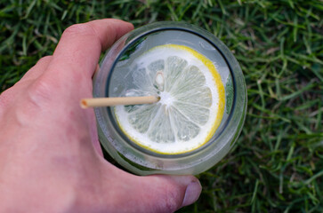 glass of lemonade with a sorbet and mint leaf on the grass