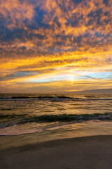 Fototapeta na wymiar Vertical image of dusk over the gulf with the sky set ablaze.