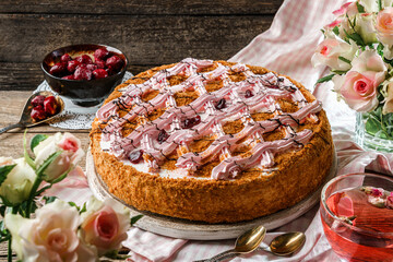 Delicious biscuit cake with cream and berries on wooden rustic background with cup of tea, flowers, napkins. Sweets, dessert and pastry, homemade cakes, close up, selective focus
