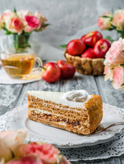 Piece of delicious cake with cream and apple jam on the plate over grey background with fresh apples and flowers. Sweets, dessert and pastry, close up, selective focus