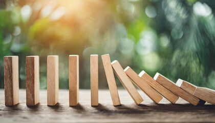 wooden block dominoes collapsing, conveying themes of resistance, risk mitigation, and the lone block standing strong