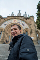 Young brunet man climbing the church stairs happily. Vertical