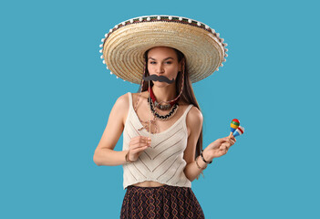 Beautiful woman in sombrero hat, with paper mustache and maracas on light blue background