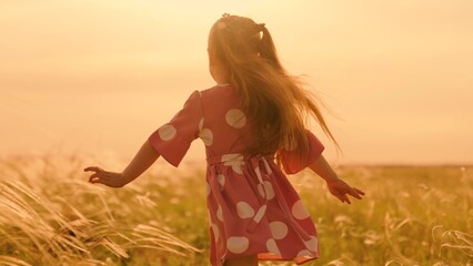 Kid runs across meadow. Happy family concept, child dream. Little girl runs on grass, in sun, slow motion. Childhood dream concept. Happy little girl playing at sunset. Happy child in field at sunset.