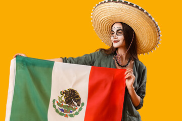 Young woman with painted skull on her face and flag against yellow background. Celebration of...