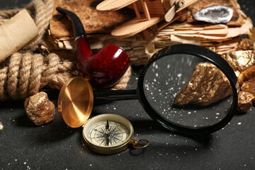 Travel equipment with smoking pipe, magnifier and golden nuggets on grunge black background