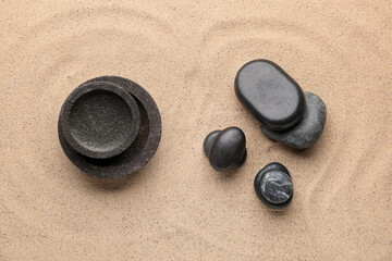 Fototapeta na wymiar Spa stones and bowls on sand background. Zen concept