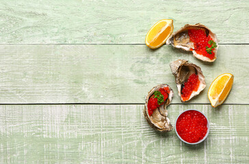 Tasty oysters with lemon and red caviar on green wooden background