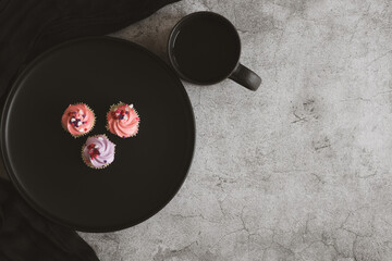 There is a plate of muffins and coffee on the table. Breakfast concept