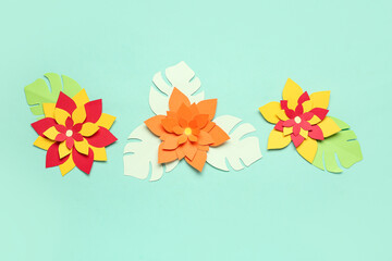 Colorful origami flowers with leaves on green background
