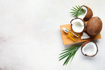 Fototapeta na wymiar Wooden board with bottle of coconut cosmetic oil and plant leaves on white background