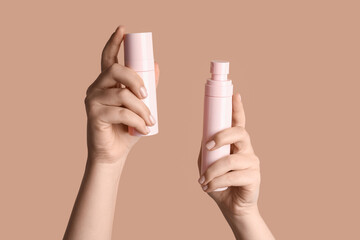 Woman holding bottles of cosmetic products on color background, closeup