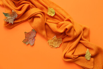 Knitted scarf with autumn leaves on orange background