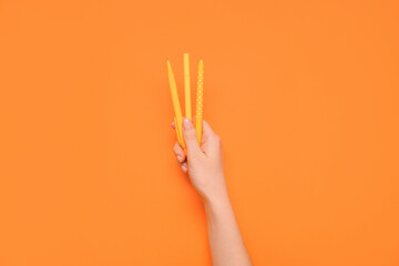Female hand holding pens on orange background