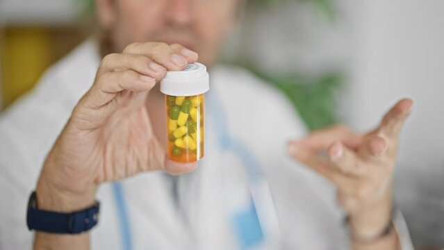 A man in a lab coat examines a pill bottle in a medical office, suggesting a healthcare setting.