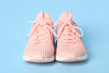 Stylish pink sneakers on blue background