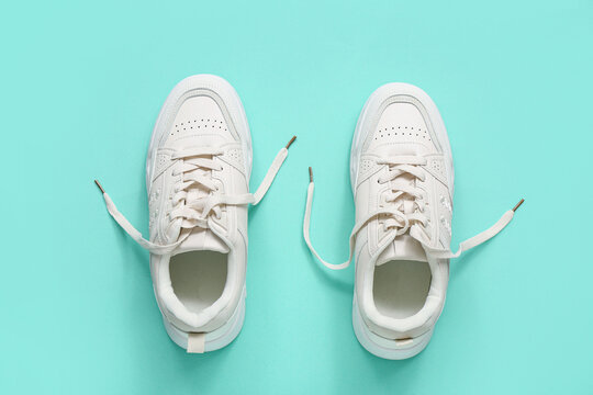 Stylish white sneakers on turquoise background