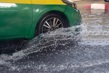 The detailed look at wheel of car driving through a flooding street the rain