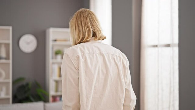 A middle-aged man with long hair using crutches navigates a modern living room, showcasing resilience and independence.