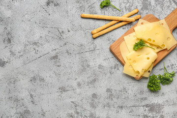 Board with tasty cheese slices, parsley and Italian Grissini on light background