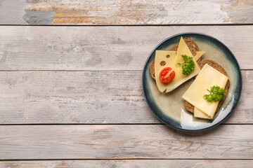 Tasty sandwiches with cheese and tomato in plate on wooden background