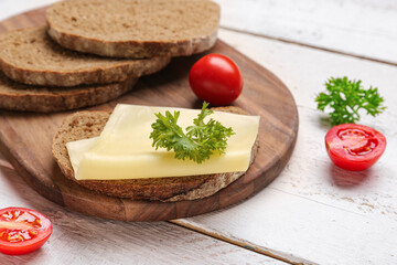 Tasty sandwich with cheese, tomatoes and parsley on light wooden background, closeup