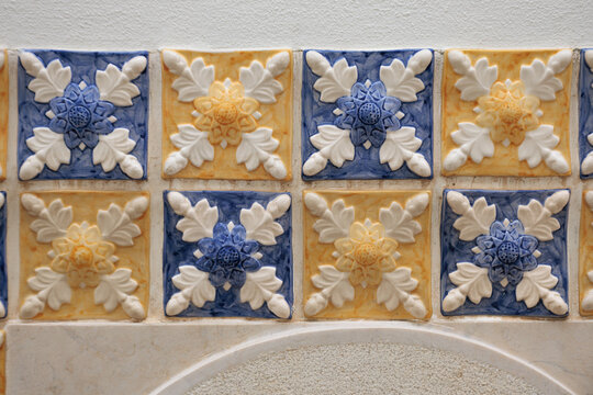 Blue and yellow floral squared mosaic of tiles with geometric shapes and sand wall copy space